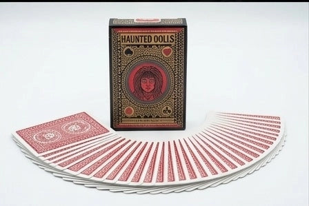 Haunted Dolls Playing Cards tuck box behind a wide fan of red and white patterned card backs