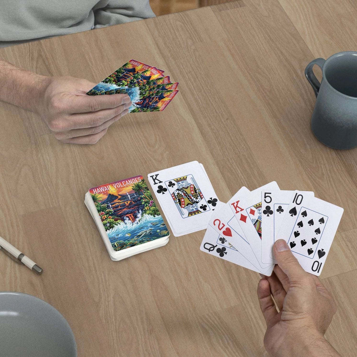 Hawai'i Volcanoes jumbo-index playing cards in use at a table with lava and Pacific Ocean card backs