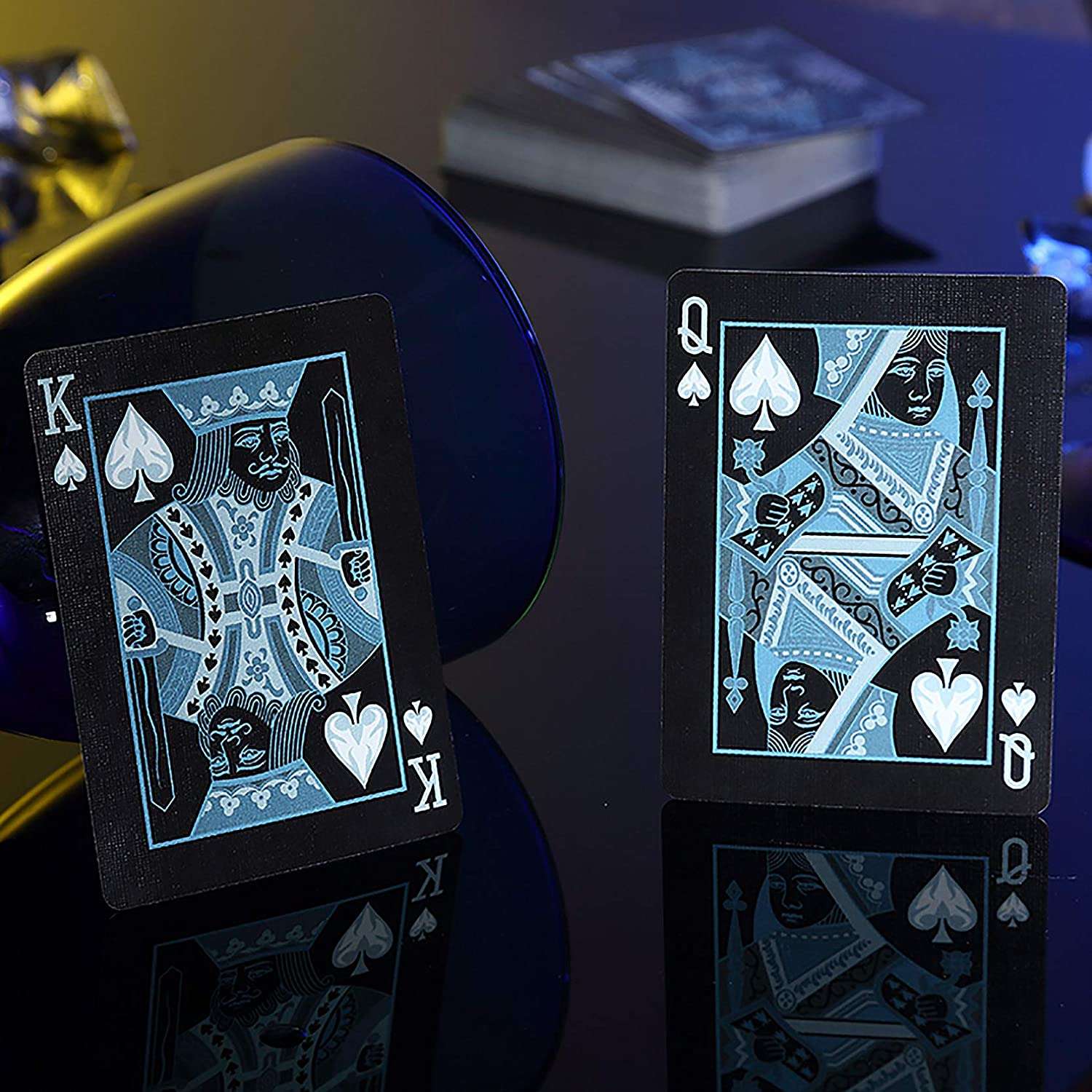 Black playing cards with blue designs on a reflective surface