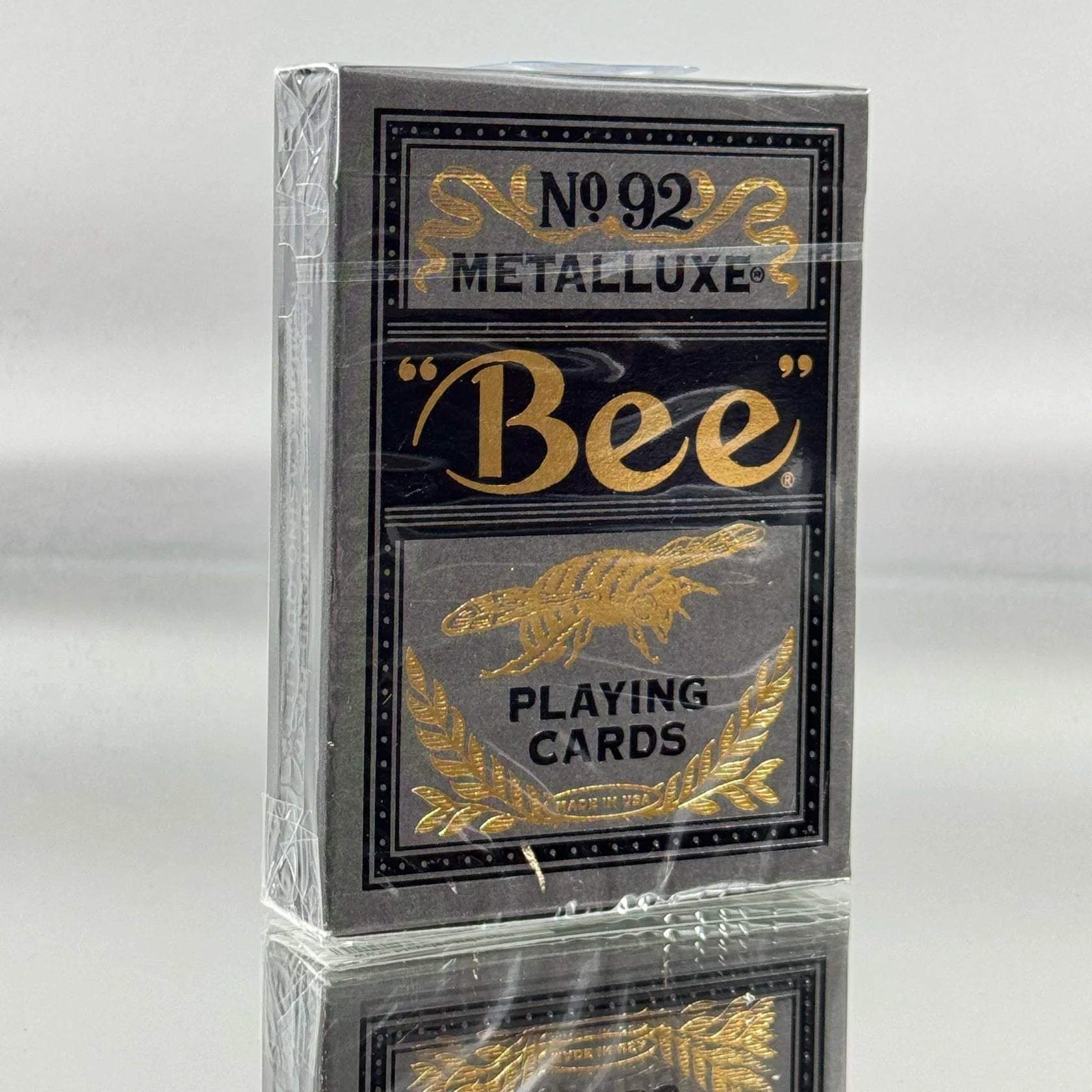 Deck of Bee metalluxe playing cards with metallic gold text on a reflective surface