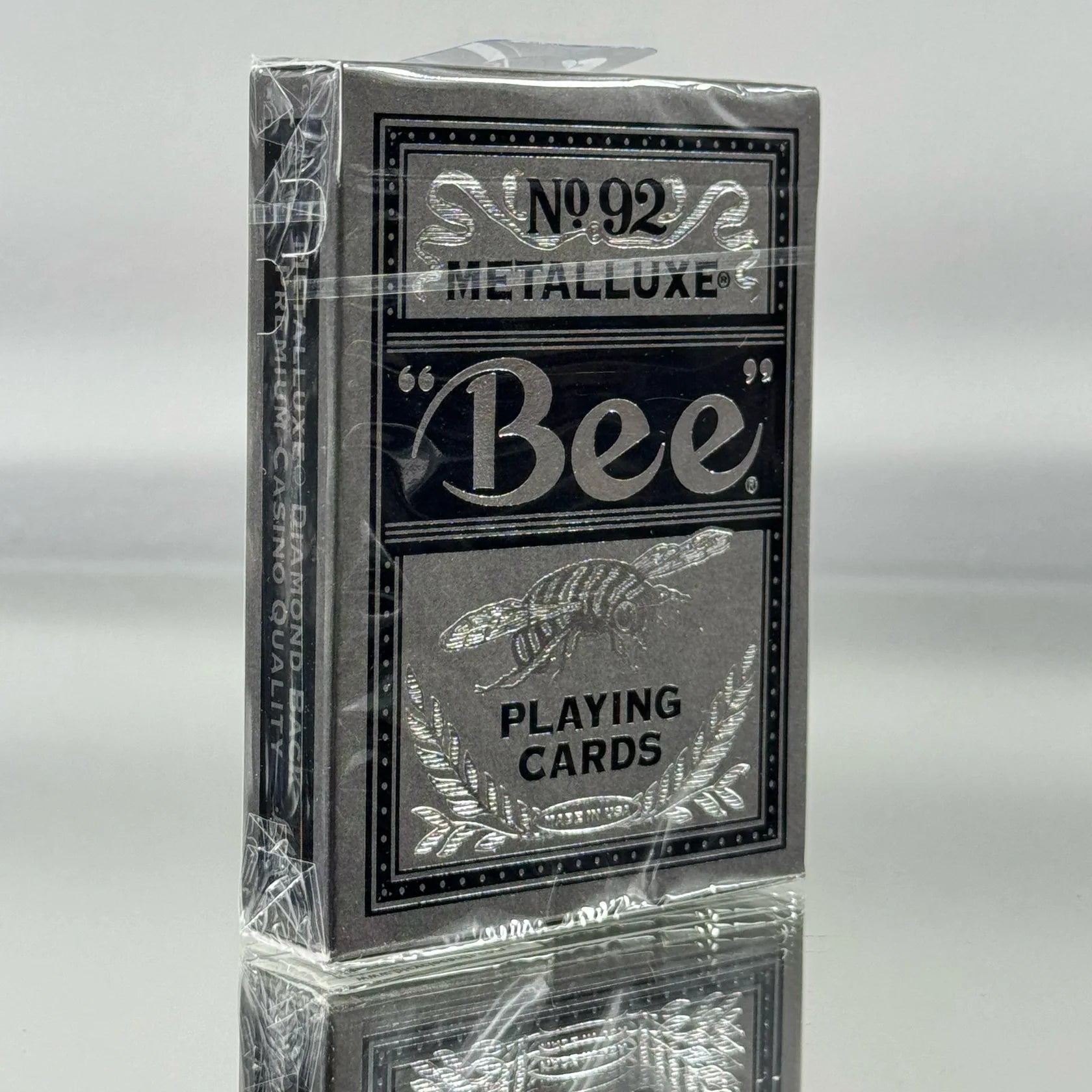 Deck of Bee silver playing cards with metalluxe finish on a reflective surface.
