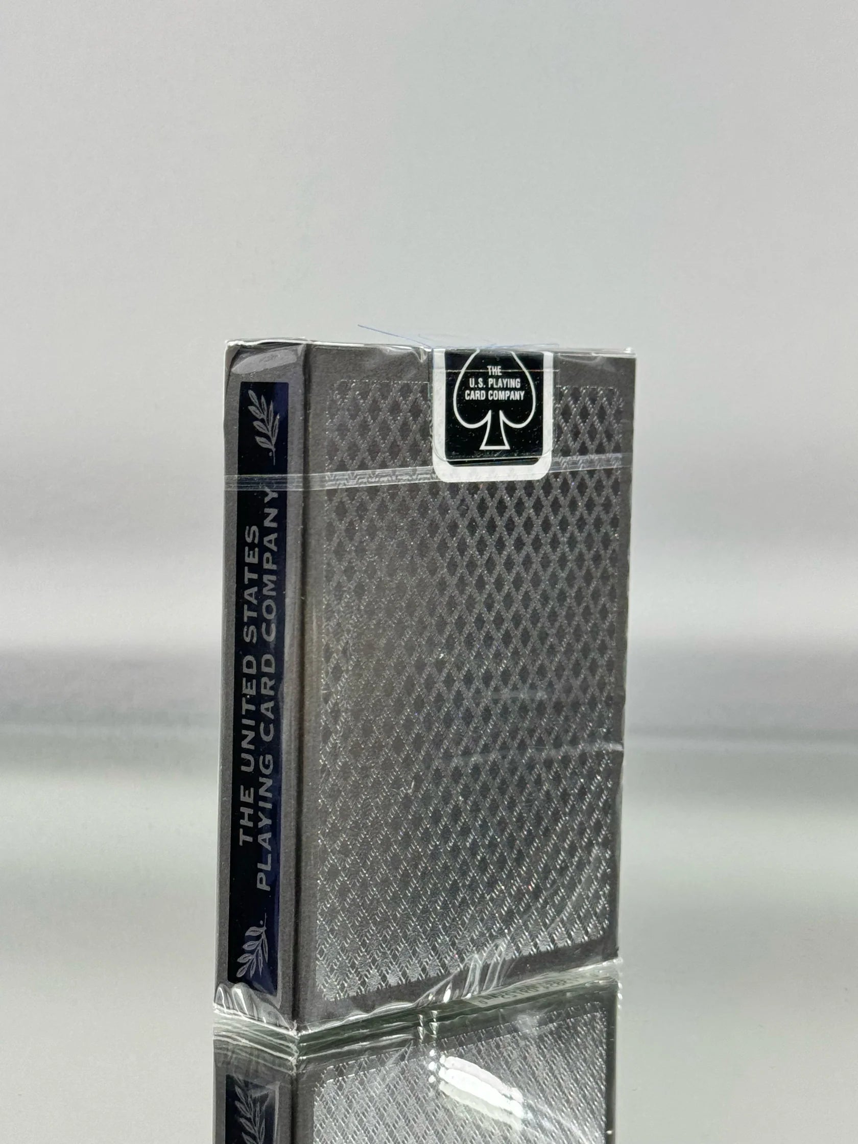 Deck of Bee silver metalluxe playing cards with a clear plastic cover on a reflective surface