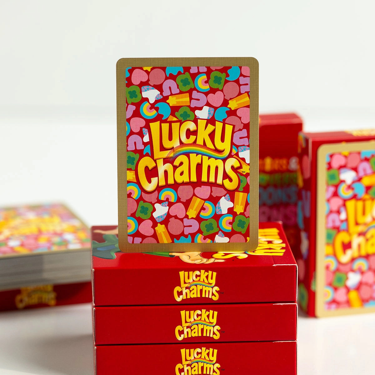 Lucky Charms card back with a gold foil border, colorful marshmallow pattern, and centered logo.