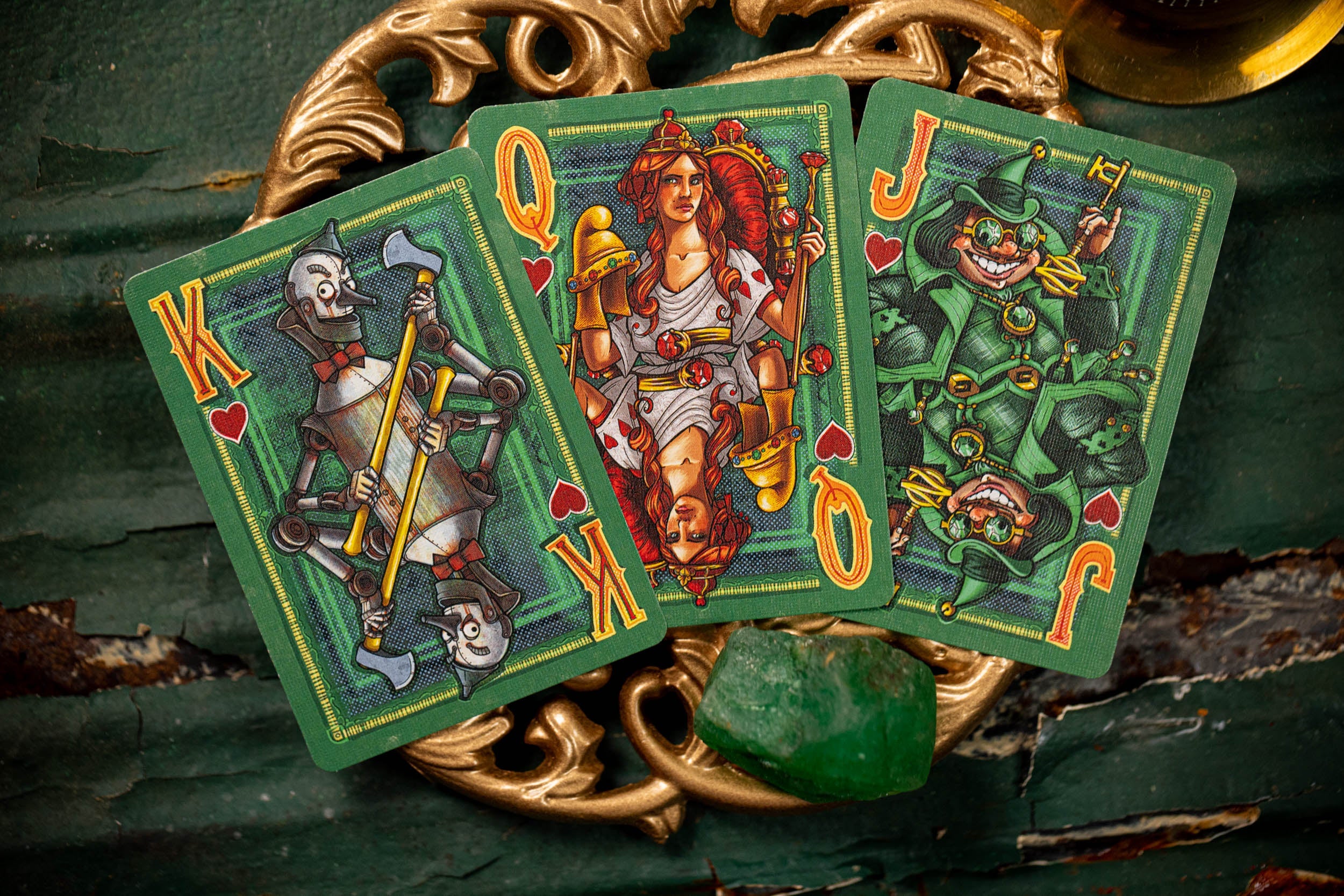 Three playing cards (King, Queen, Jack) on a decorative background with gold elements.