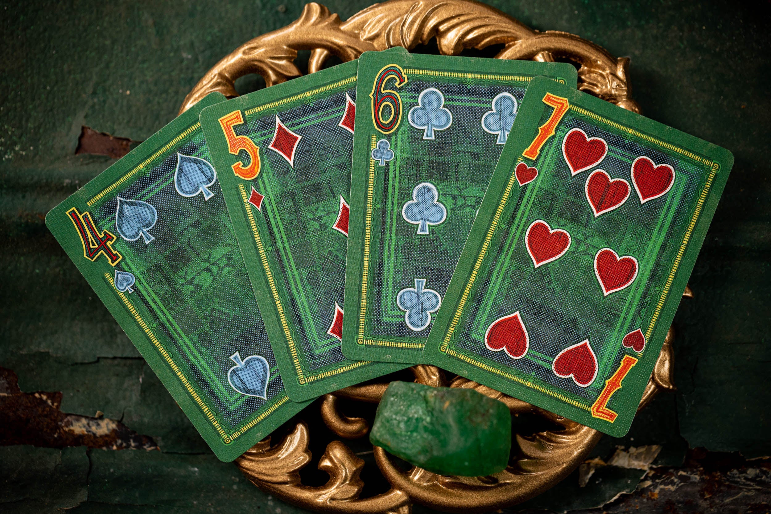 Green playing cards with gold borders on a dark background