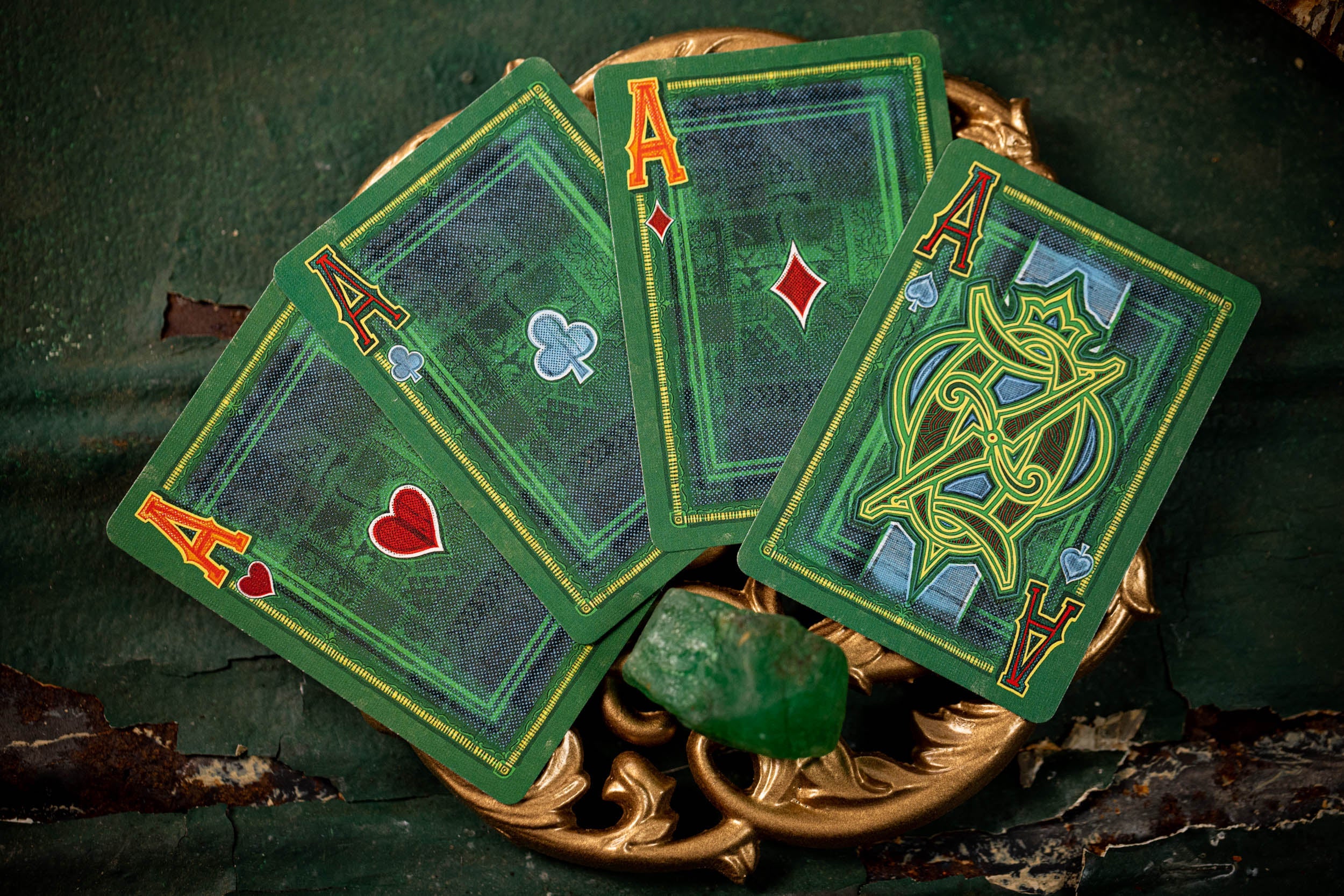 Four aces from different suits on green playing cards with a decorative stand.