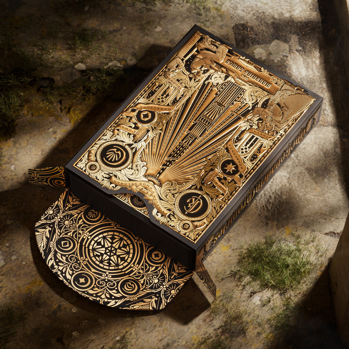 Open theory11 Kovadrin tuck box with gold tower artwork and a patterned circular flap resting on stone.