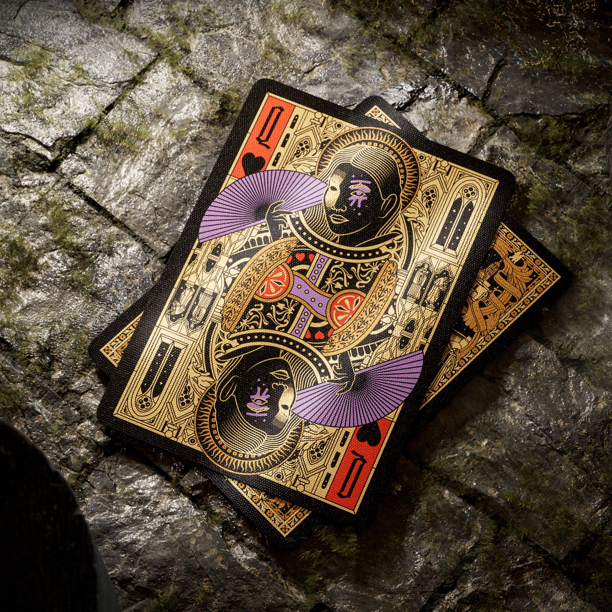 Theory11 Kovadrin Queen of Hearts holding a purple fan, with mirrored gold, red, and black artwork above a card back.