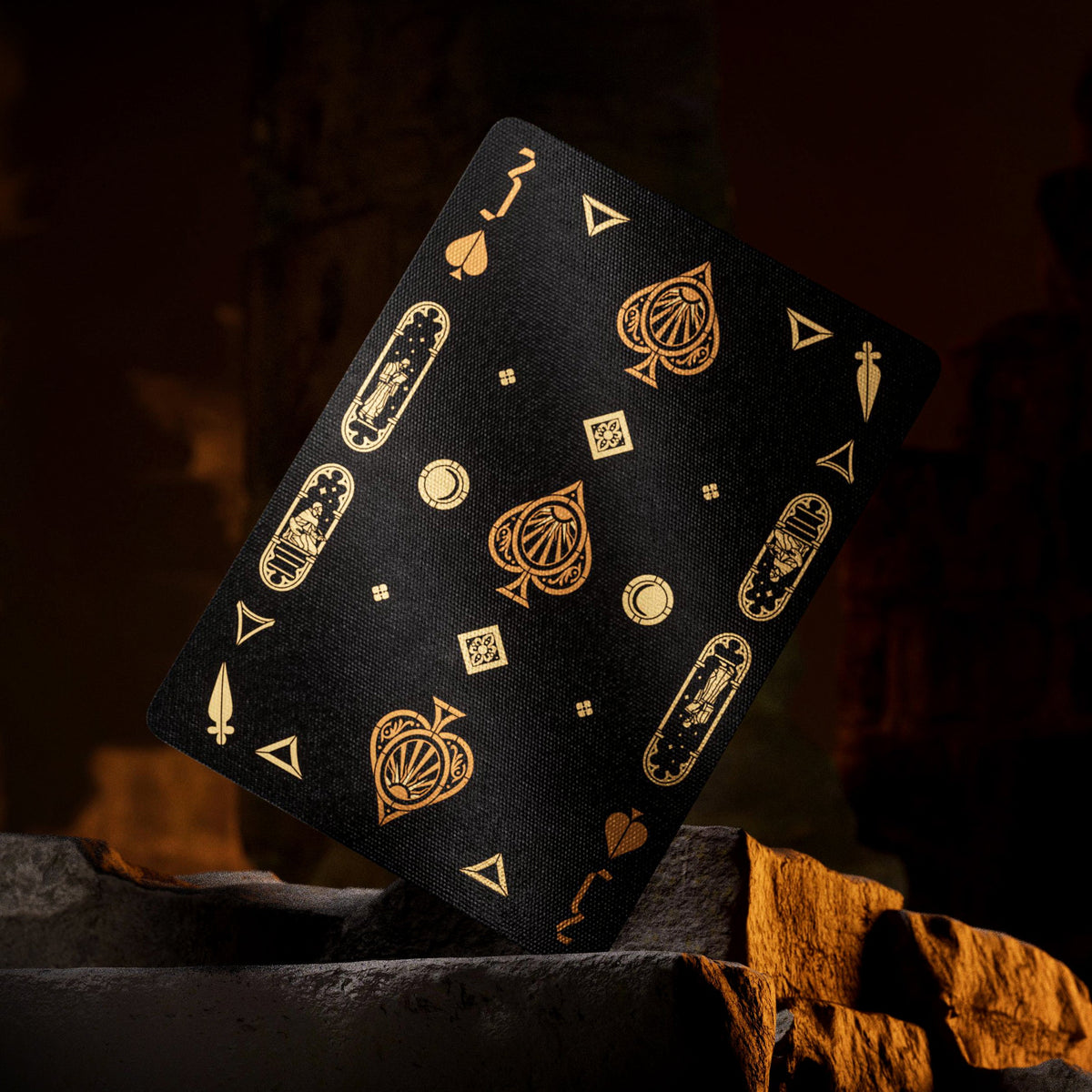 Theory11 Kovadrin Three of Spades with gold ornamental pips, geometric symbols, and small figures on a textured black face.