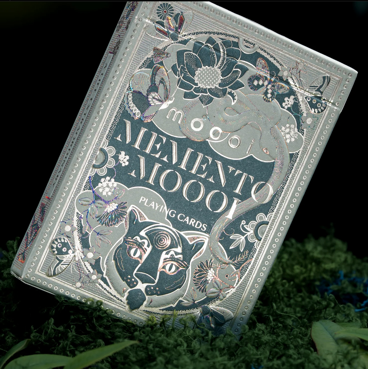 Angled front of the theory11 Memento Moooi tuck box with reflective foil, flowers, a serpent, and a feline face.