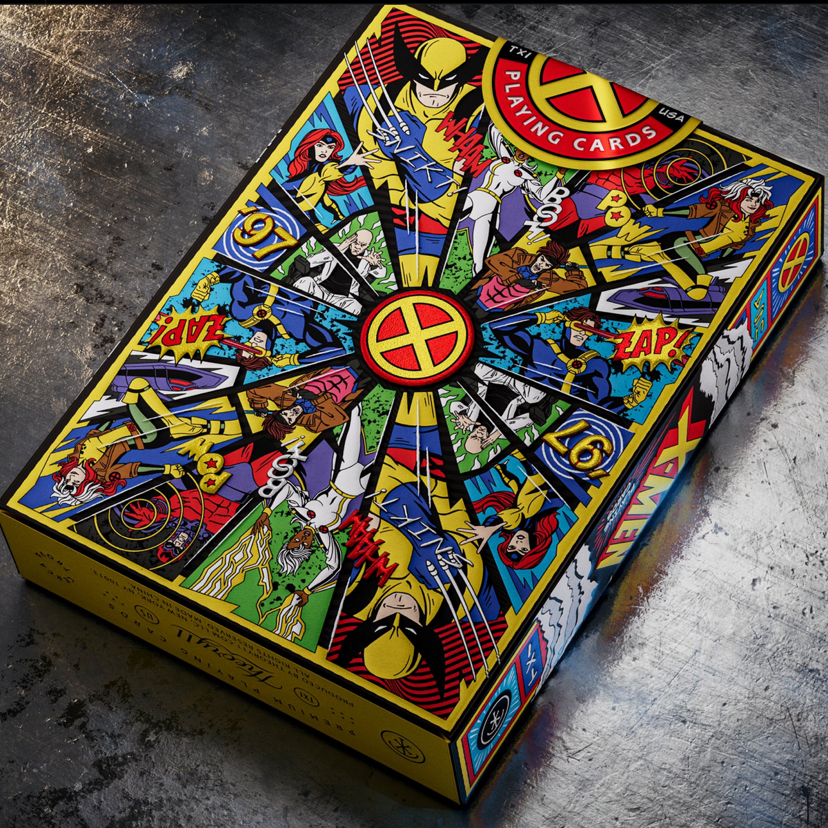 Theory11 X-Men tuck box lying rear-side up on a metal surface, showing the mirrored character artwork and yellow edging.